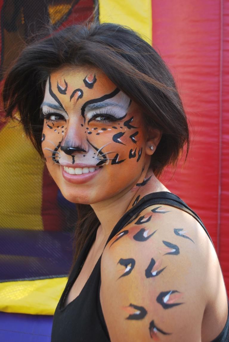 Gepard som applicerar smink till kvinna med ansikte och kroppsmakeup för Halloween och karneval