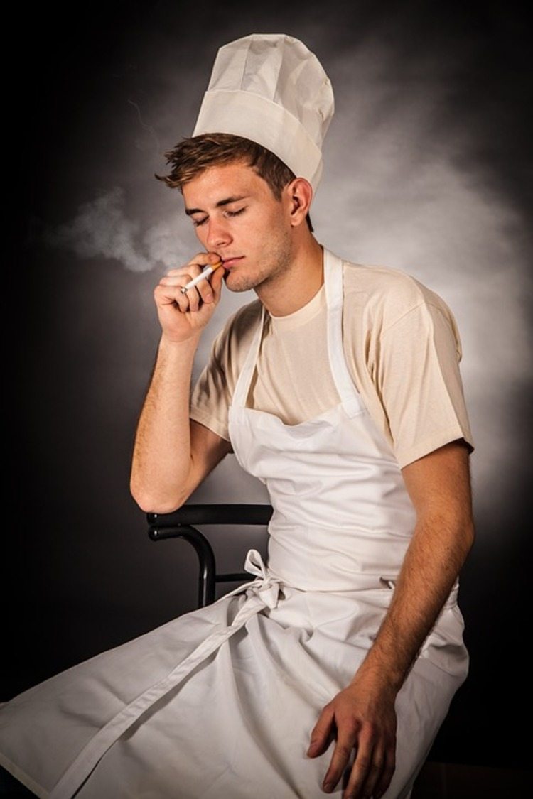 laga mat med hatt och vitt förkläde röker en cigarett