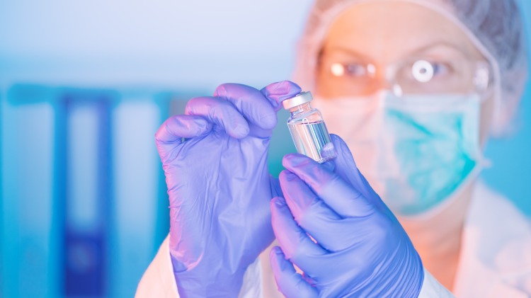 forskare undersöker en flaska mmr-vaccination mot covid-19-symptom