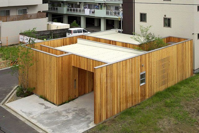 minimalistisk-hus-omgiven-av-flera-berättelse-bostadshus-arbol-design