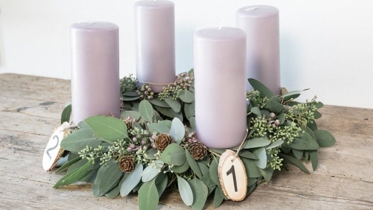 Moderna adventsarrangemang gör jularrangemang med lavendelljus och lagergrenar och kottar och träskivor