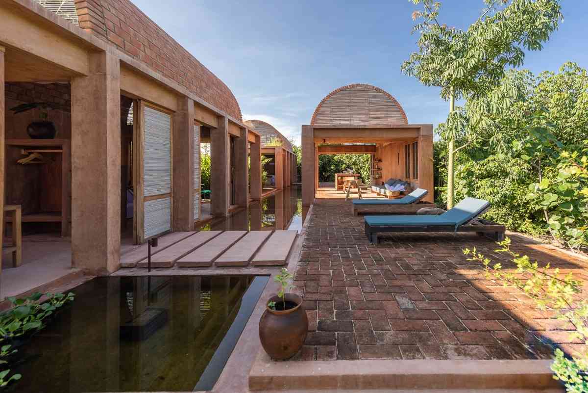relaxavdelning vid poolen med solstolar och tre moderna tegelhus