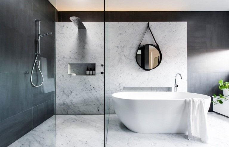 Moderna badrum i grått med väggplattor i granit och ett fristående badkar och rund spegel och duschkabin med en glasskiva