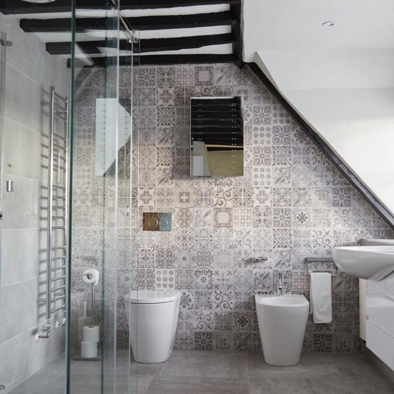 Moderna badrum med sluttande tak skapar idéer med lapptäckta mosaikplattor och en duschkabin