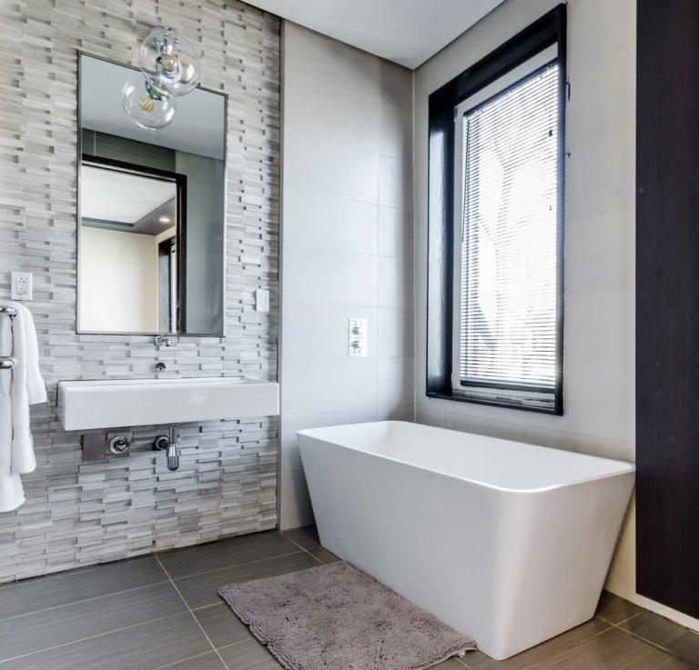 Moderna badrum i grått med väggar klädda i natursten med ett fristående badkar utan basenhet