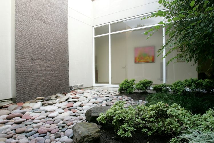 modern-trädgård-design-stenar-växter-flodstenar-betong-vägg-fönsterfront