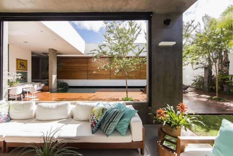 modern-trädgård-design-trä fasad-soffa-vit-klädsel-trä-ram-kudde-färgglada-fönster-vägg