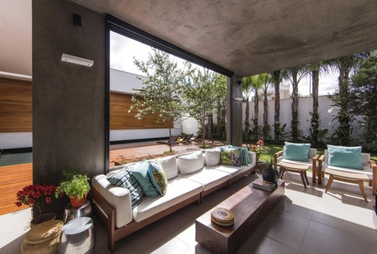 modern-trädgård-design-träfasad-vardagsrum-ljus-dagsljus-sittplatser-klädsel-vita-blommor-växter
