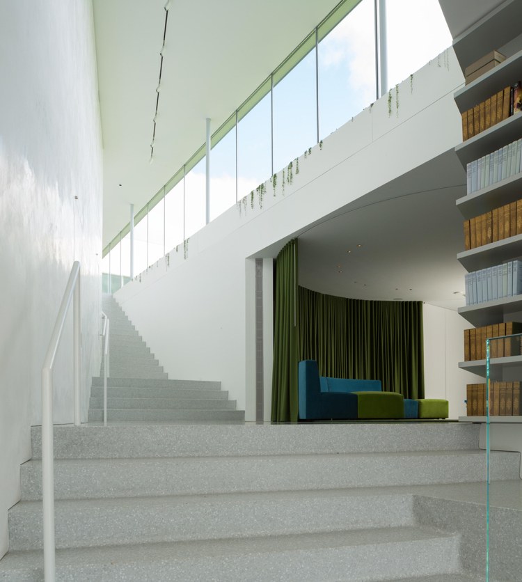 Modern glasfront - grönska - trappor - betong - glasräcke - bokhyllor