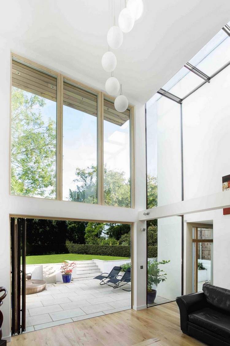 rymligt-vardagsrum-högt i tak-vita-väggar-trädgård