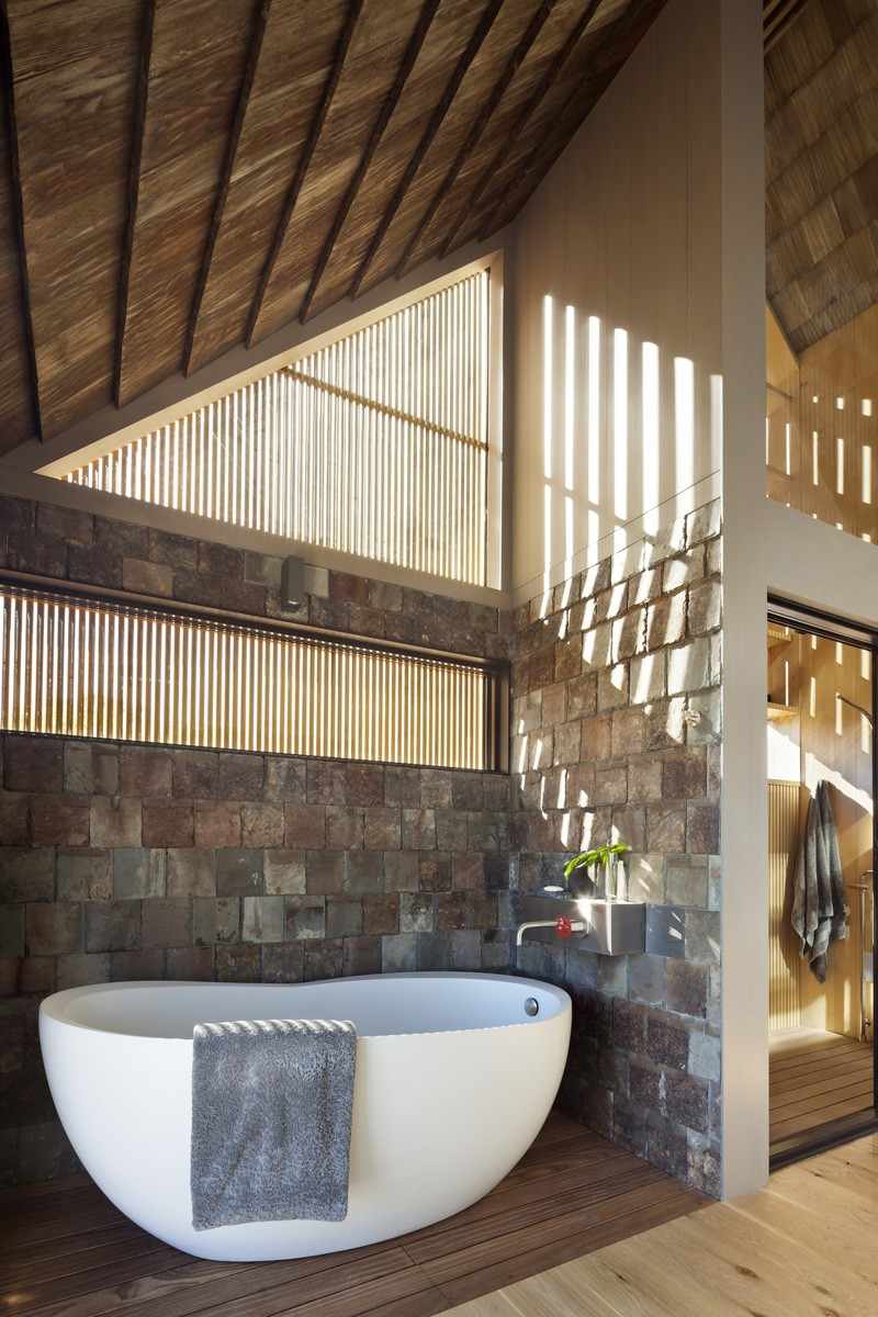 modern träfasad-träbältros-badrum-fristående-badkar-asfaltering-natursten-trägolv