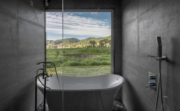Badrum glasvägg utsikt badkar väggpaneler betong utseende