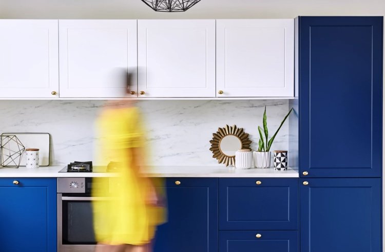 modernt kök i mörkblått vitt och marmor med mässingshandtag
