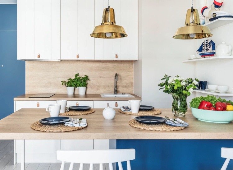 Mörkblå vägg och köksö kombinerat med vita köksfronter, bänkskiva i trä och bakvägg i trä