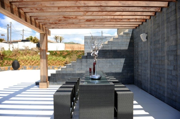 modern-pergola-rottingmöbler-betongterrass-natursten-vägg