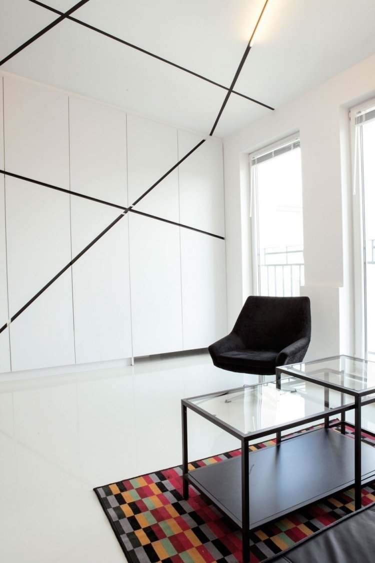 väggdesign-svart-vitt-vardagsrum-inbyggt skåp-tak-linjer-matta-färgad-fåtölj