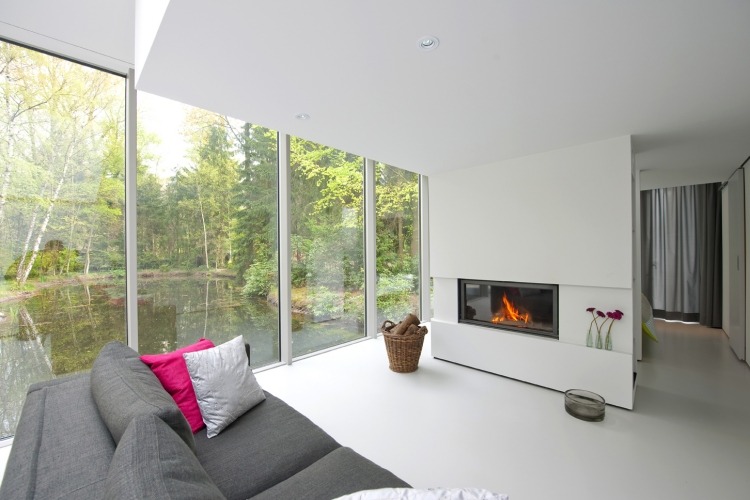 Eldstad-modernt-vardagsrum-minimalistisk-vit-panoramafönster-soffa-korg-ved