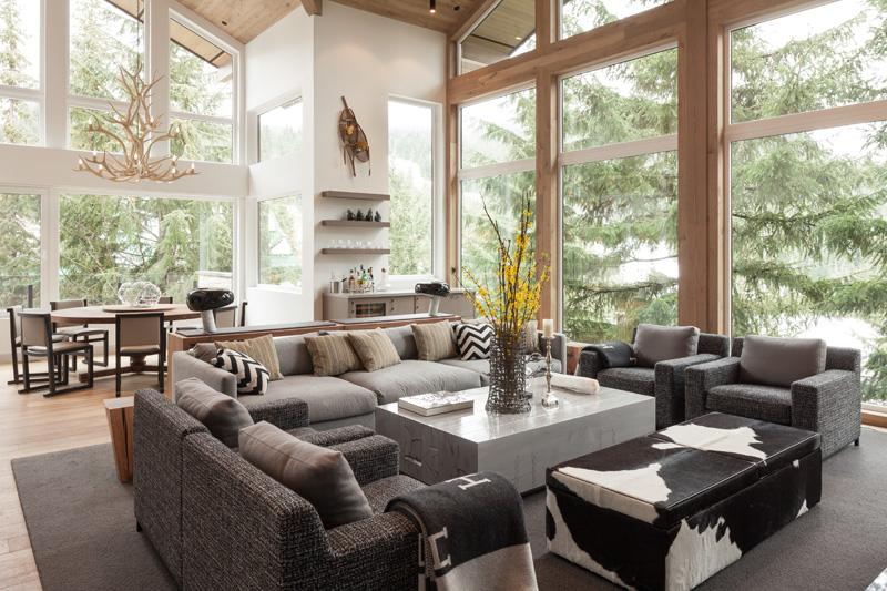 Modern lantlig stil - ombyggnad - almhaus - vardagsrum - soffa - fåtölj - grå - skog - fönsterfront - vas - soffbord