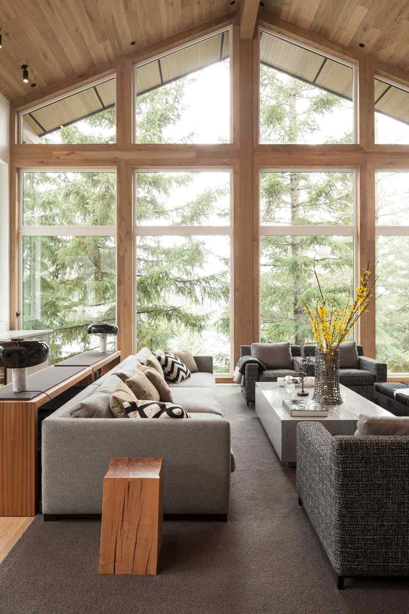 Modernt hus på landet stil-konvertering-almhaus-vardagsrum-soffa-fåtölj-grå-klädsel-vas-soffbord-fönsterfronter