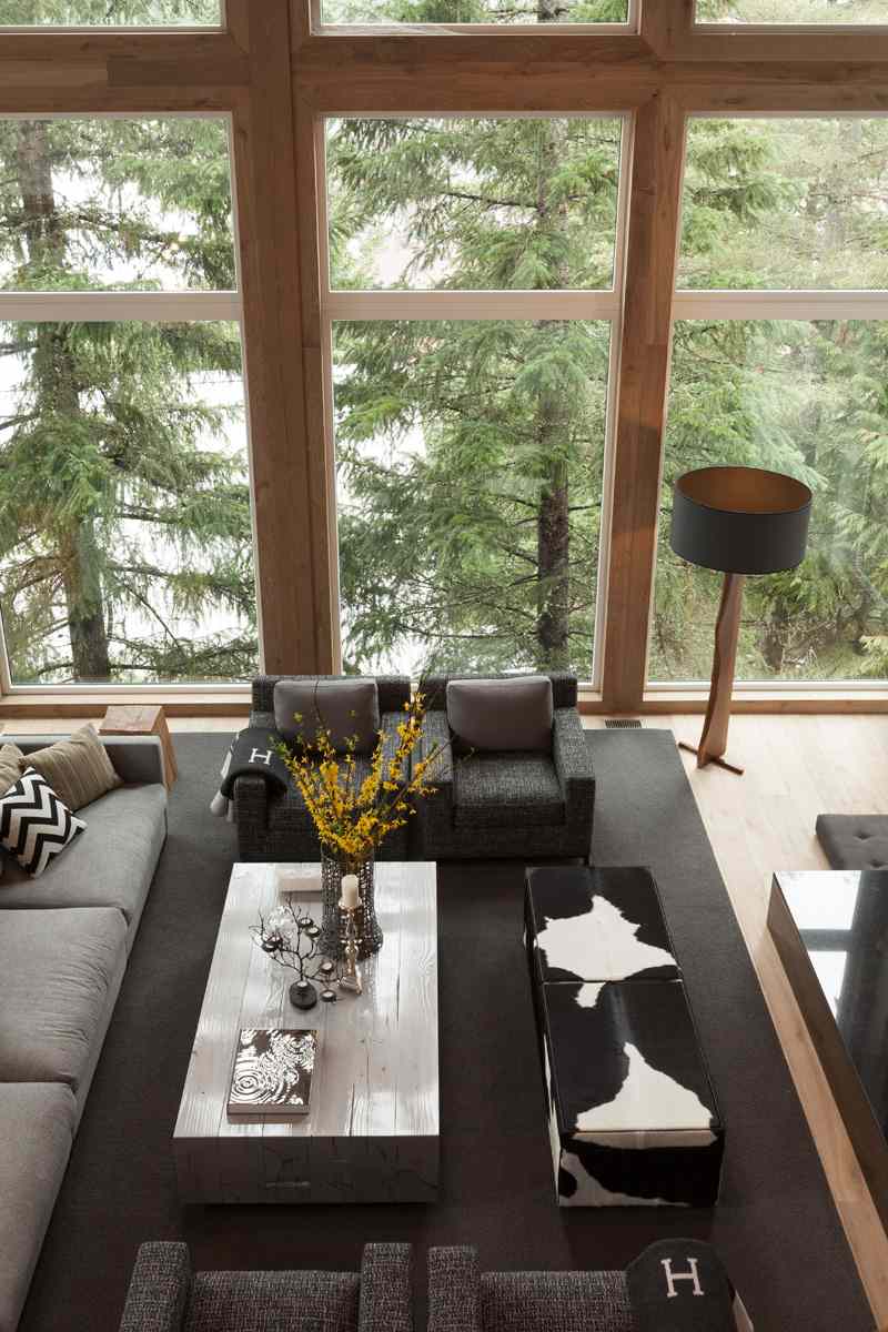 modern-land-stil-konvertering-almhaus-vardagsrum-soffbord-ljusgrå-sittplatser-grå-klädsel-trä-skog-fönsterfronter