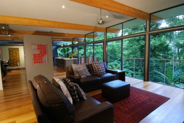modernt hus i skogen vardagsrum skinnsoffa ramlösa glasfönster