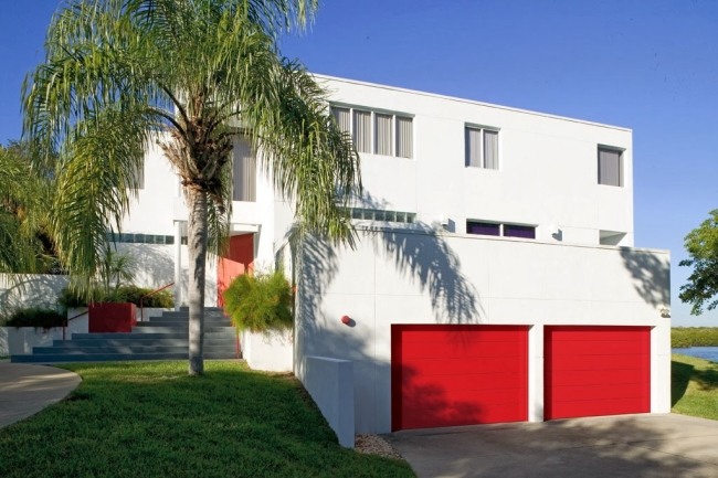 modernt hus vit fasad röda garageportar accent