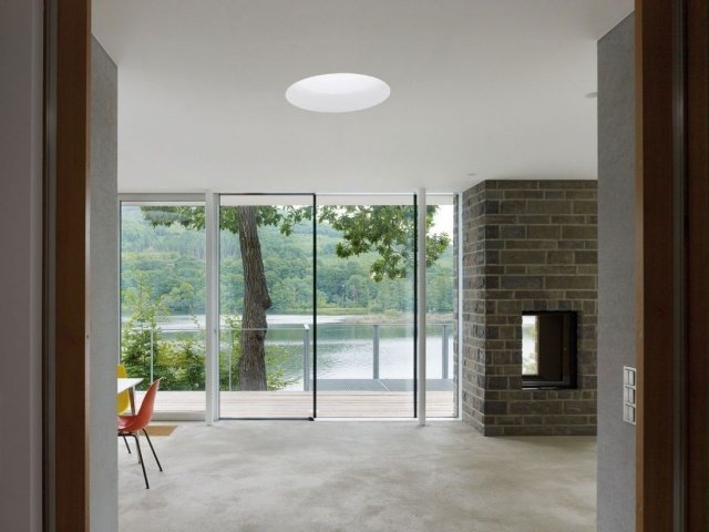 modernt hus-sjö-interiör-glas-skjutdörrar-öppen spis-stenpaneler