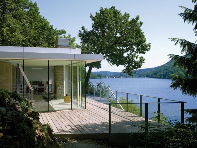 modernt hus vid sjön-glaswaende-trä-terrass-panoramautsikt