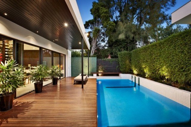 Modernt hus med pool trä terrass sekretess skärm häck planter