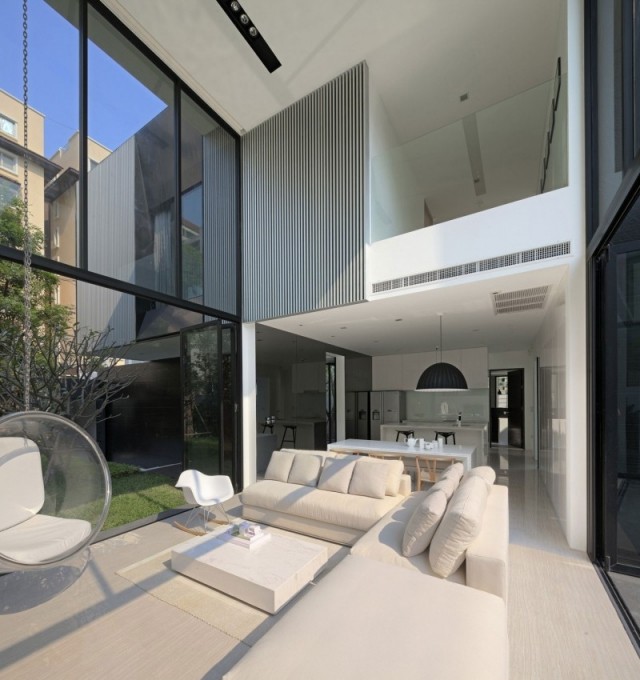modernt hyreshus glasväggar solljus vita möbler vardagsrum