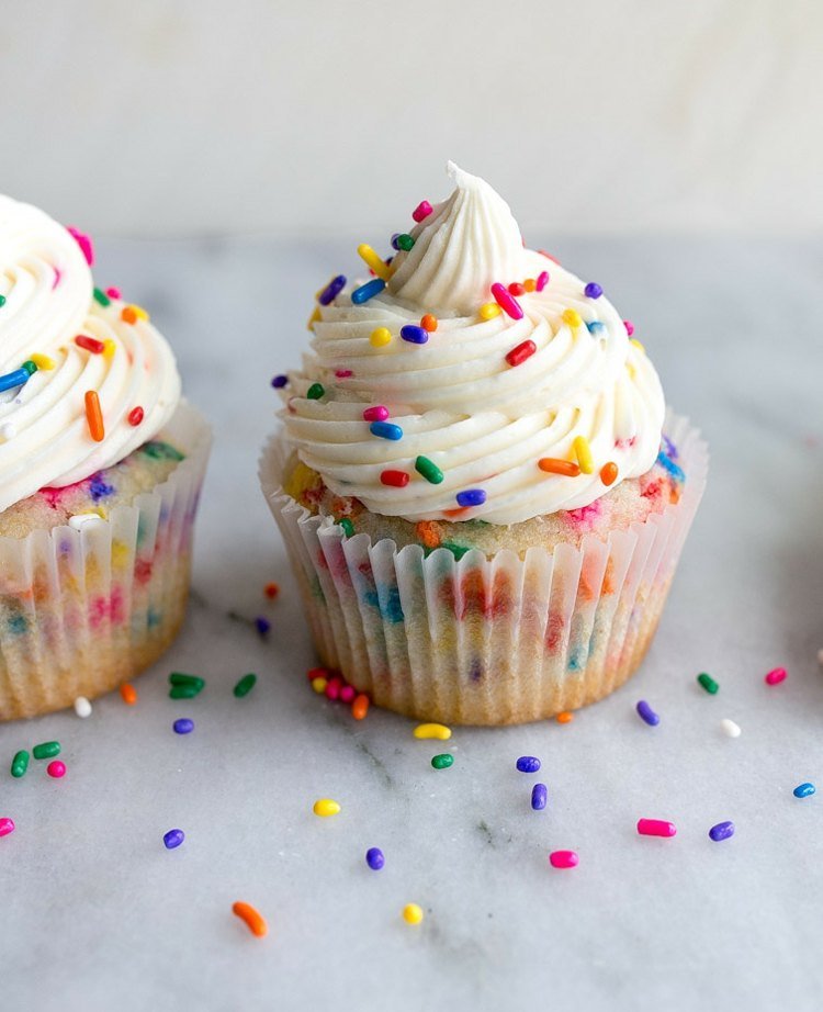 Baka färgglada muffins med strössel i smeten och på grädden