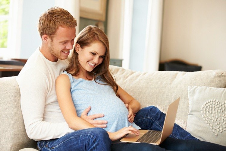 Namn på tvillingar par-man-kvinna-gravid-soffa-vardagsrum-bärbar dator-kuddar