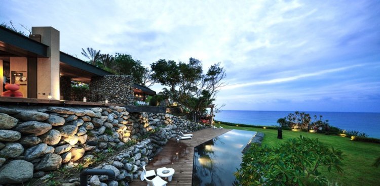 Naturstenar och stenblock -moderna-arkitektur-terrass-havsutsikt-infinity-pool-belysning