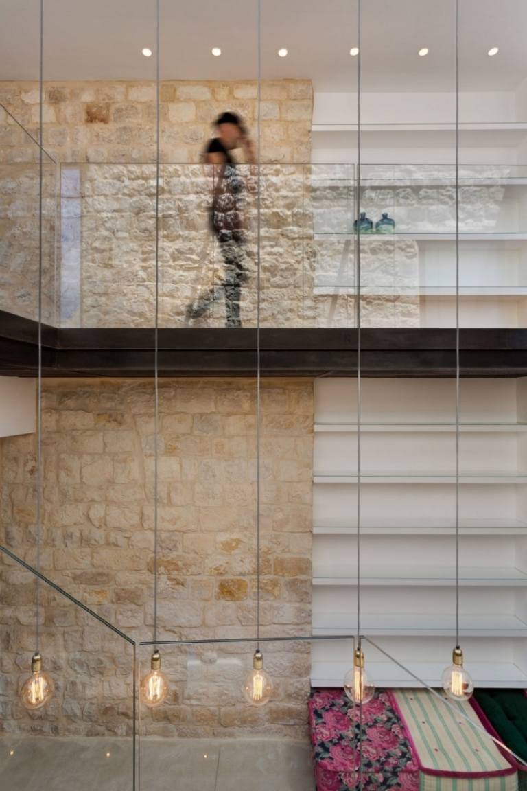 Naturstenmur inuti och utvändigt-murade stålkabel-glödlampor-glas räcken-golv-hyllor-sittdynor