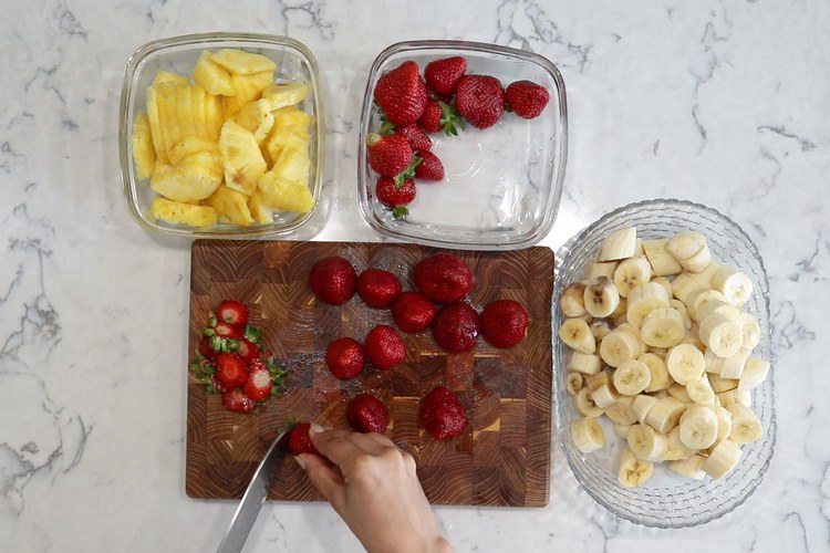 ingredienser till nicecream gjord av bananer skär jordgubbar och ananas i bitar