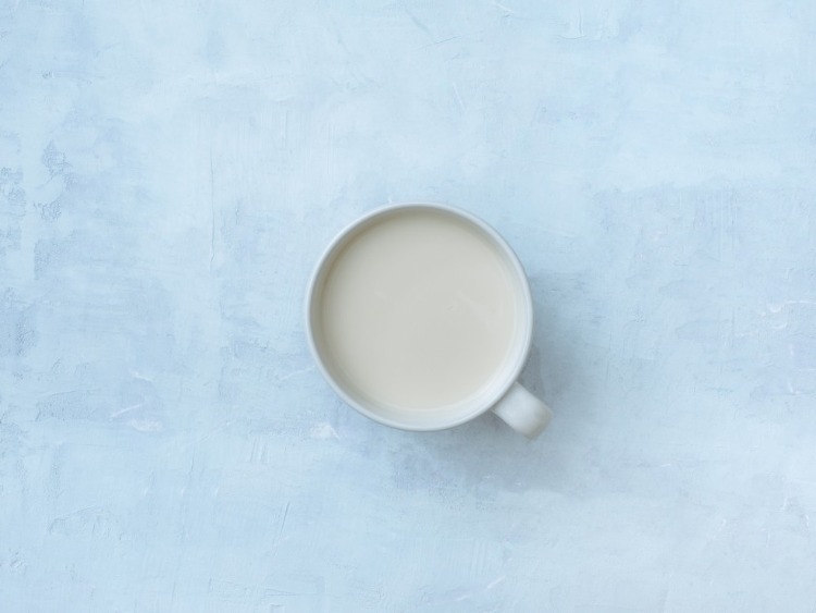 en kopp full med rå mjölk sett uppifrån