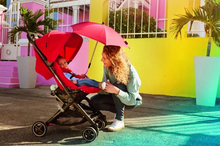 Barnvagn med små hjul och ett rött parasoll