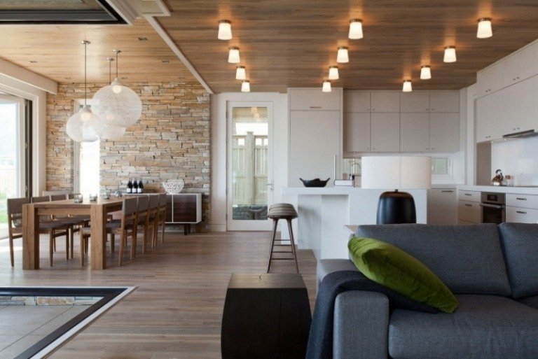 öppet-kök-vardagsrum-lampor-trätak-trägolv-soffa-grå-klädsel-matbord-massivt trä