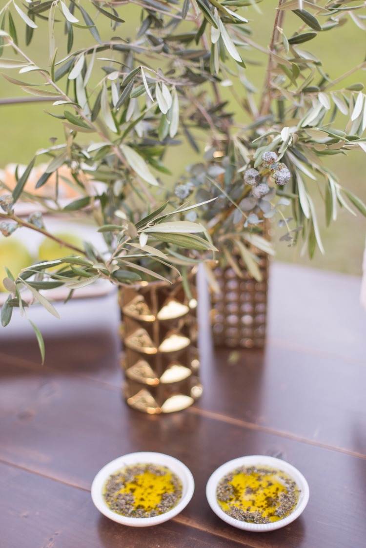 torra trädgrenar i vaser bredvid extrakt av olivblad med örter i små skålar