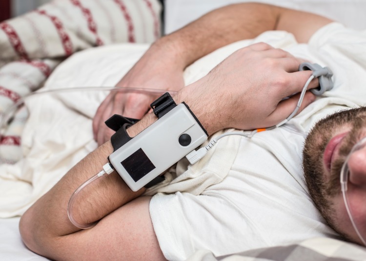 man sover med medicinsk utrustning på armen som utför sömnforskning