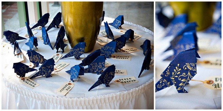 Bröllopsgäster ger origami fåglar av mörkblått papper med ett blomstermotiv