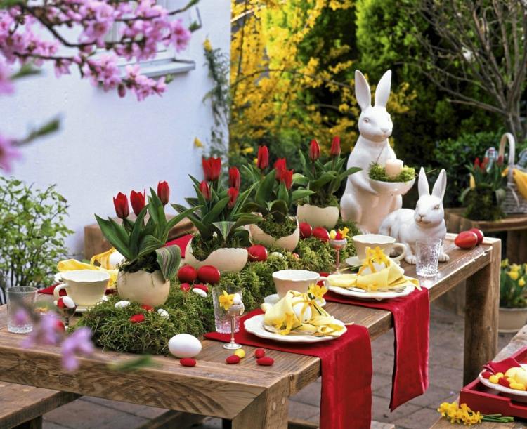 Vackra bordsdekorationer i rött och grönt till påsk med tulpaner och kaniner
