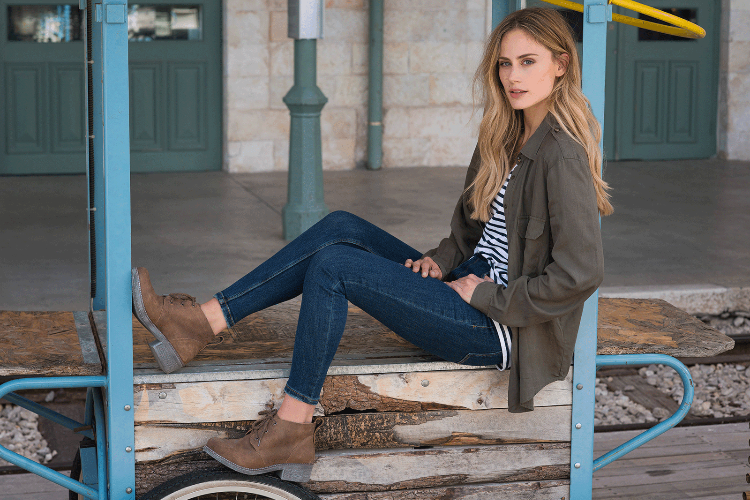 kvinna sitta jeans skjorta höga skor klackar sko klackar rustik brun trä vagn tåg station spår