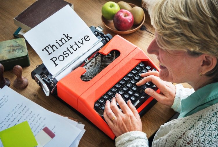 äldre kvinna som använder skrivmaskin uppmuntrar positivt tänkande