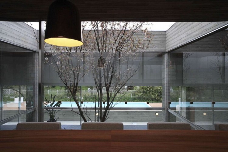 Panoramafönster till innergården -minimalistisk-matbord-stolar-hängande-lampa-trä-betong