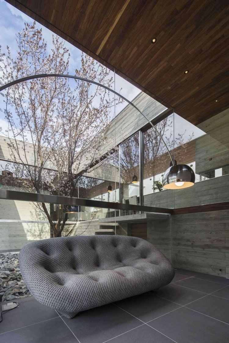 Panoramafönster till innergården -minimalistisk-soffa-golvlampa-betong-takpaneler