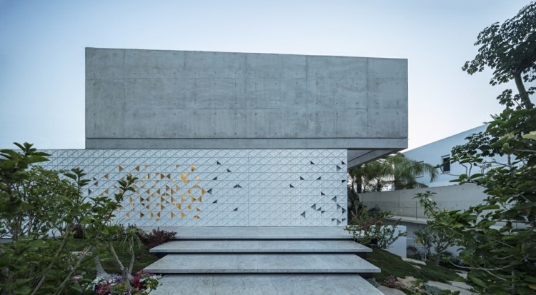 perforerad husfasad av aluminiumvita trianglar mönster exponerade betongtrappor betongträdgård grön