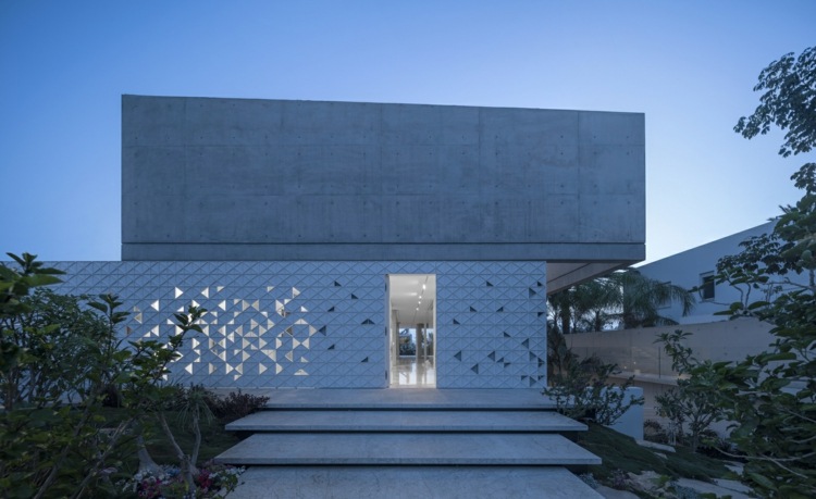 perforerad fasad vit aluminium geometriska mönster trianglar ljusa skuggor exponerade betong i en vinkel
