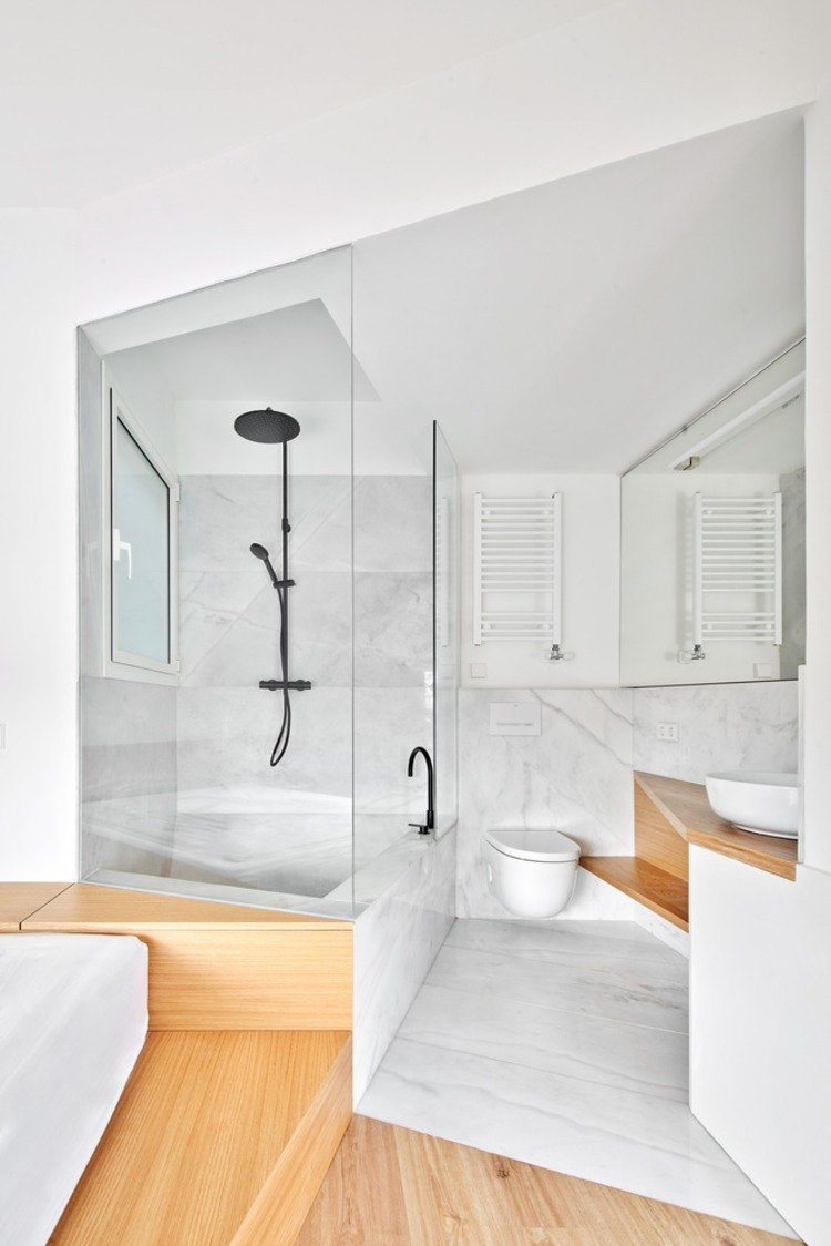 litet badrum klädt i marmor och trä med en glasvägg