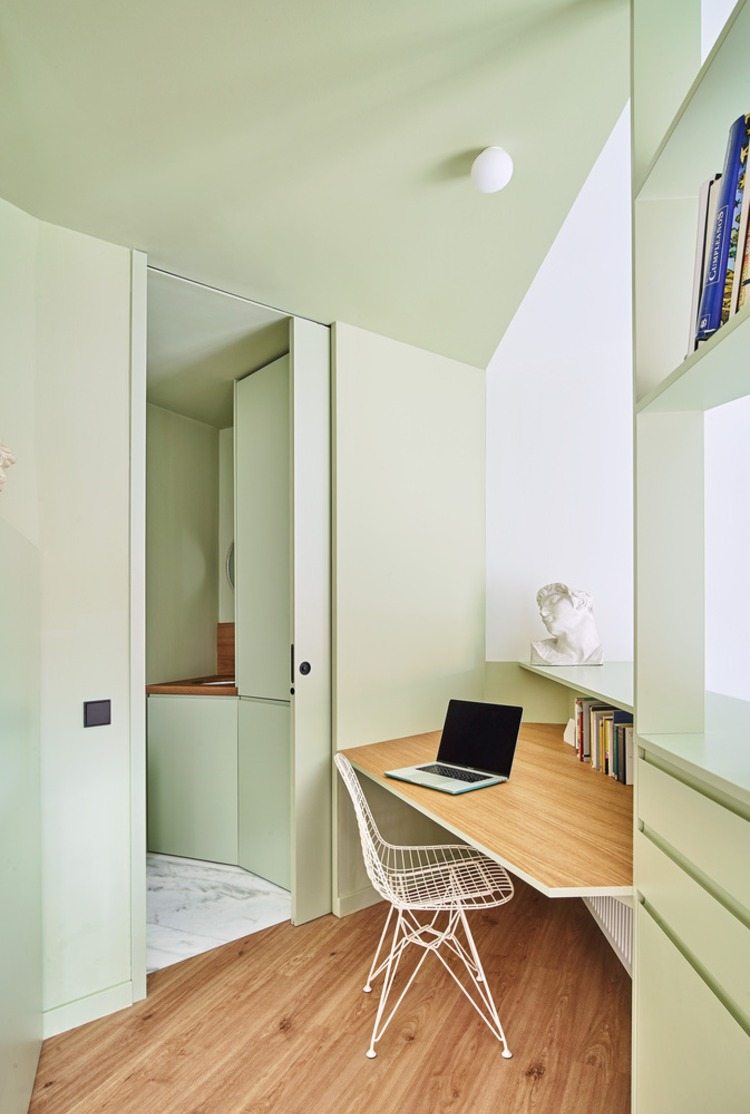 övergång från köket till ett litet hörn med en bärbar dator och ett skrivbord med en modern design